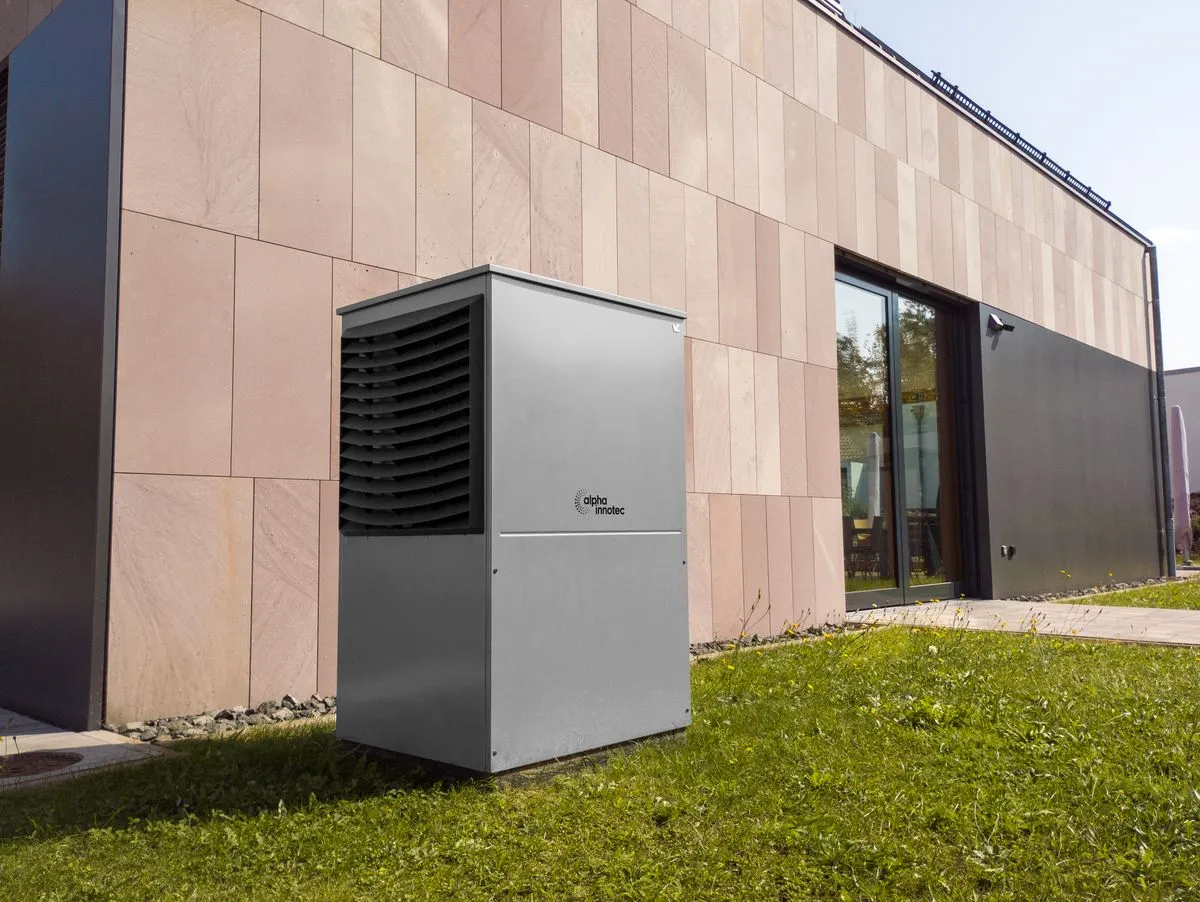 Pompe à chaleur monobloc installée sur une pelouse devant un bâtiment moderne